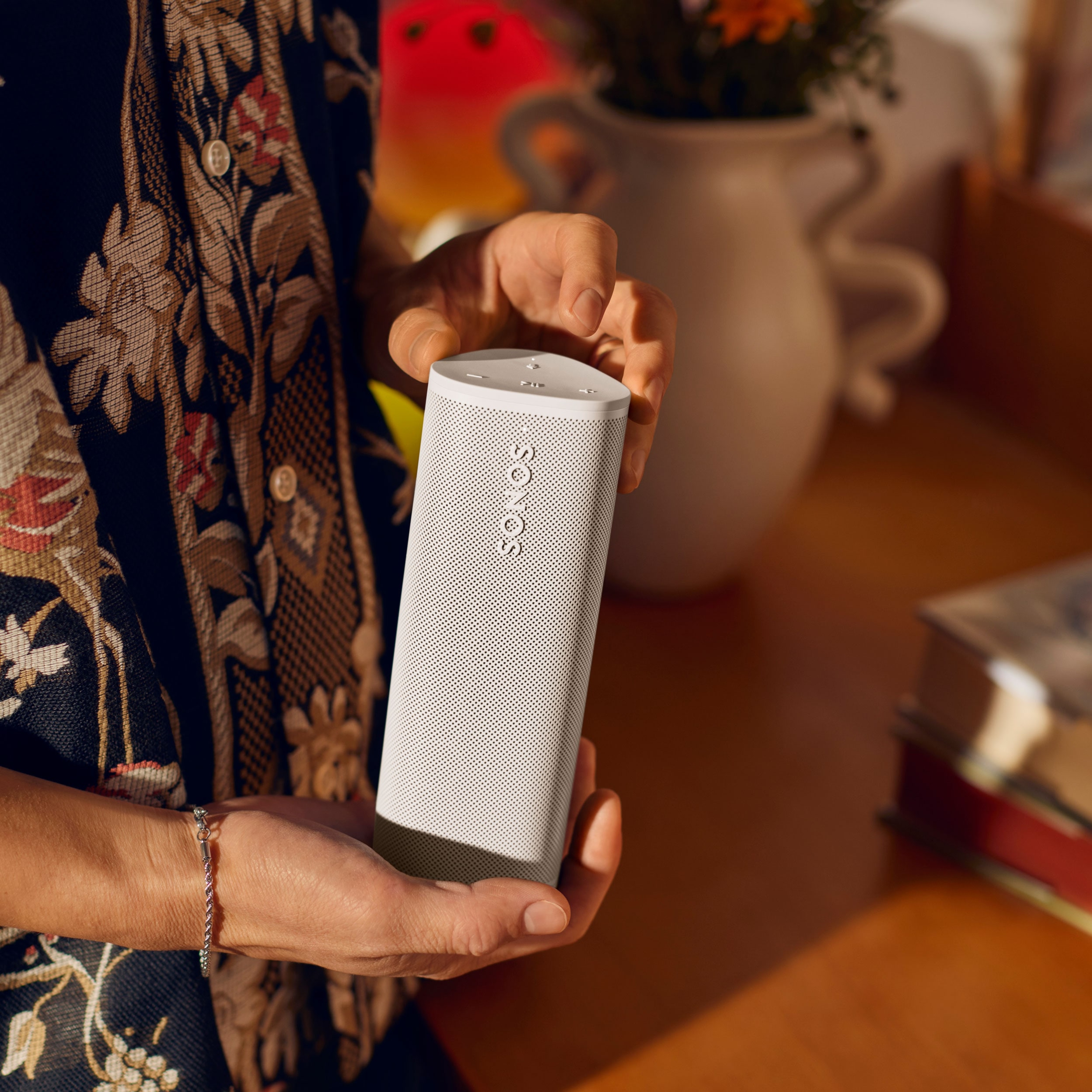 Nahaufnahme einer Person mit einem Sonos Roam 2 in Weiß