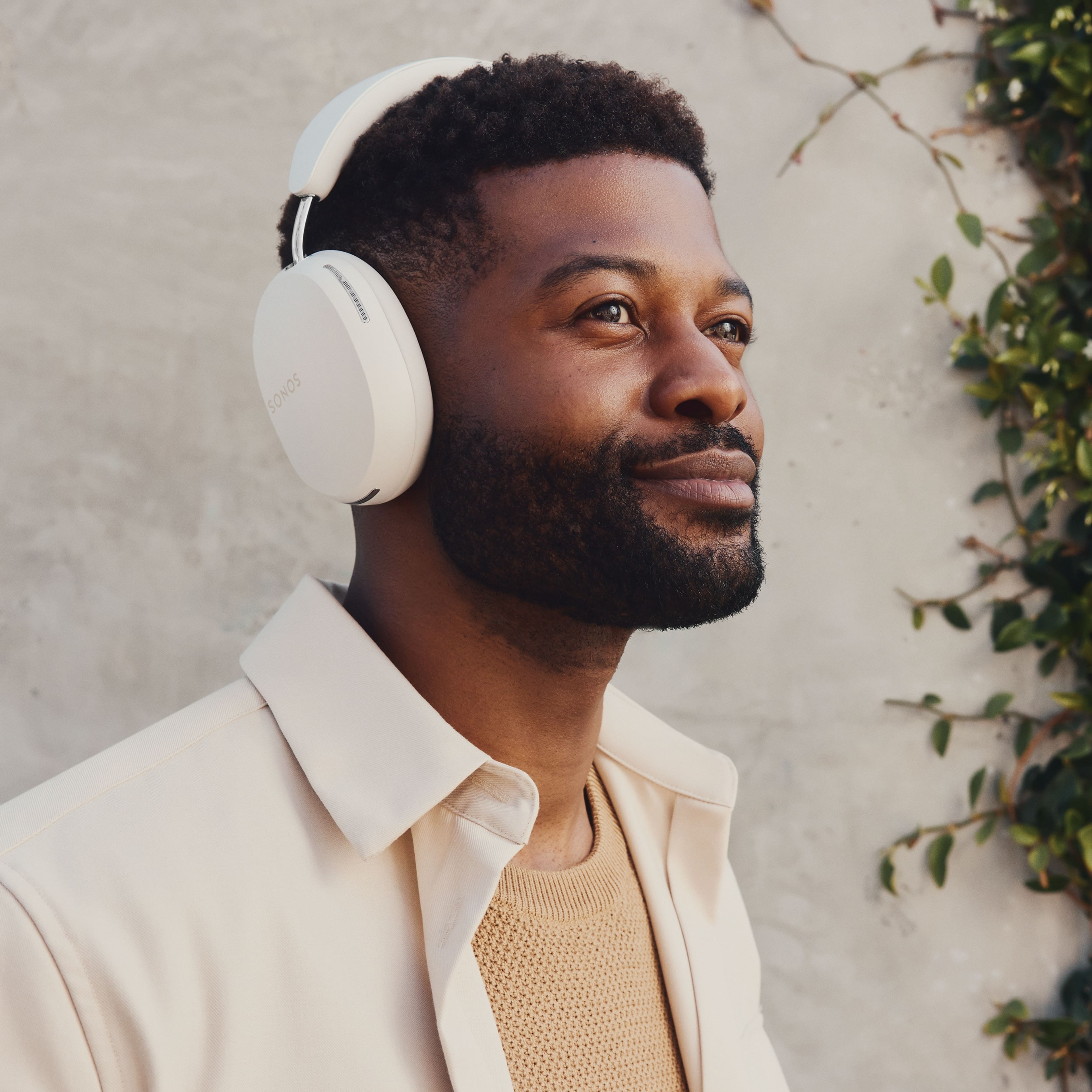 Une personne écoutant de la musique avec un casque audio Sonos Ace blanc