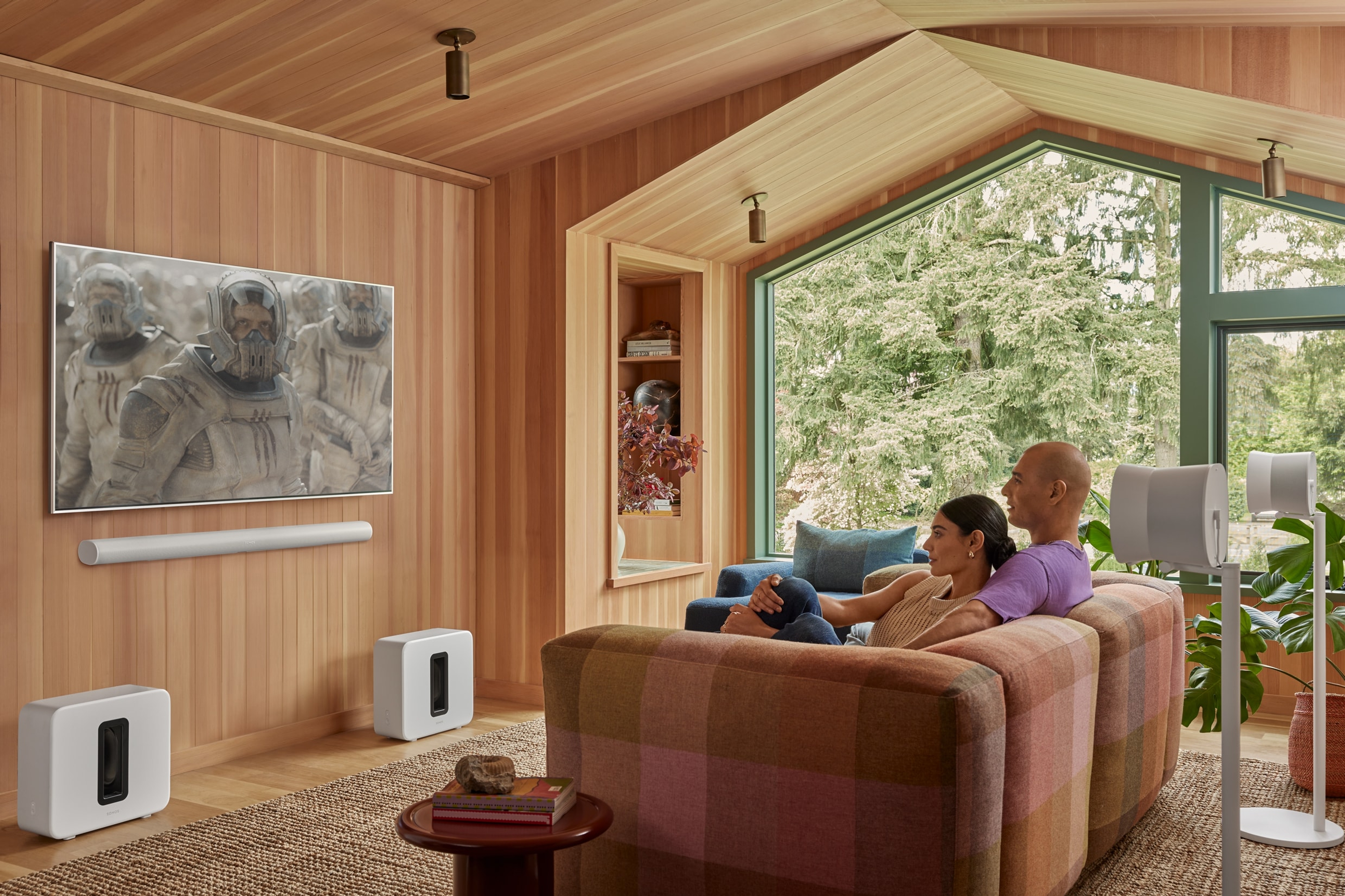 Para oglądająca telewizję w salonie i zestaw kina domowego (Sonos Arc Ultra, dwa Sub 4 i dwa Era 300)