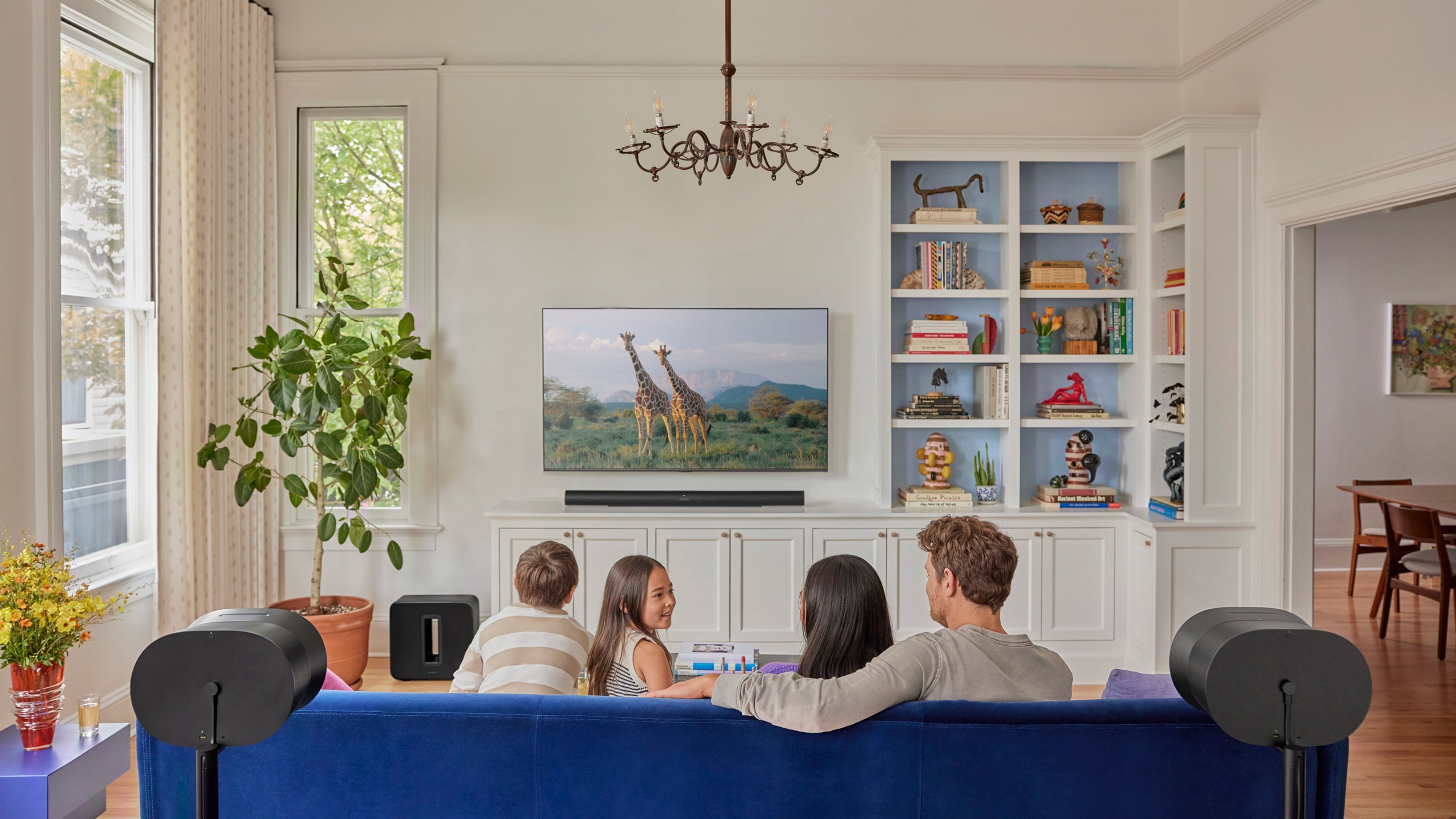 Famille en train de regarder la TV avec une Sonos Arc Ultra, un Sonos Sub 4 et deux Sonos Era 300 en noir