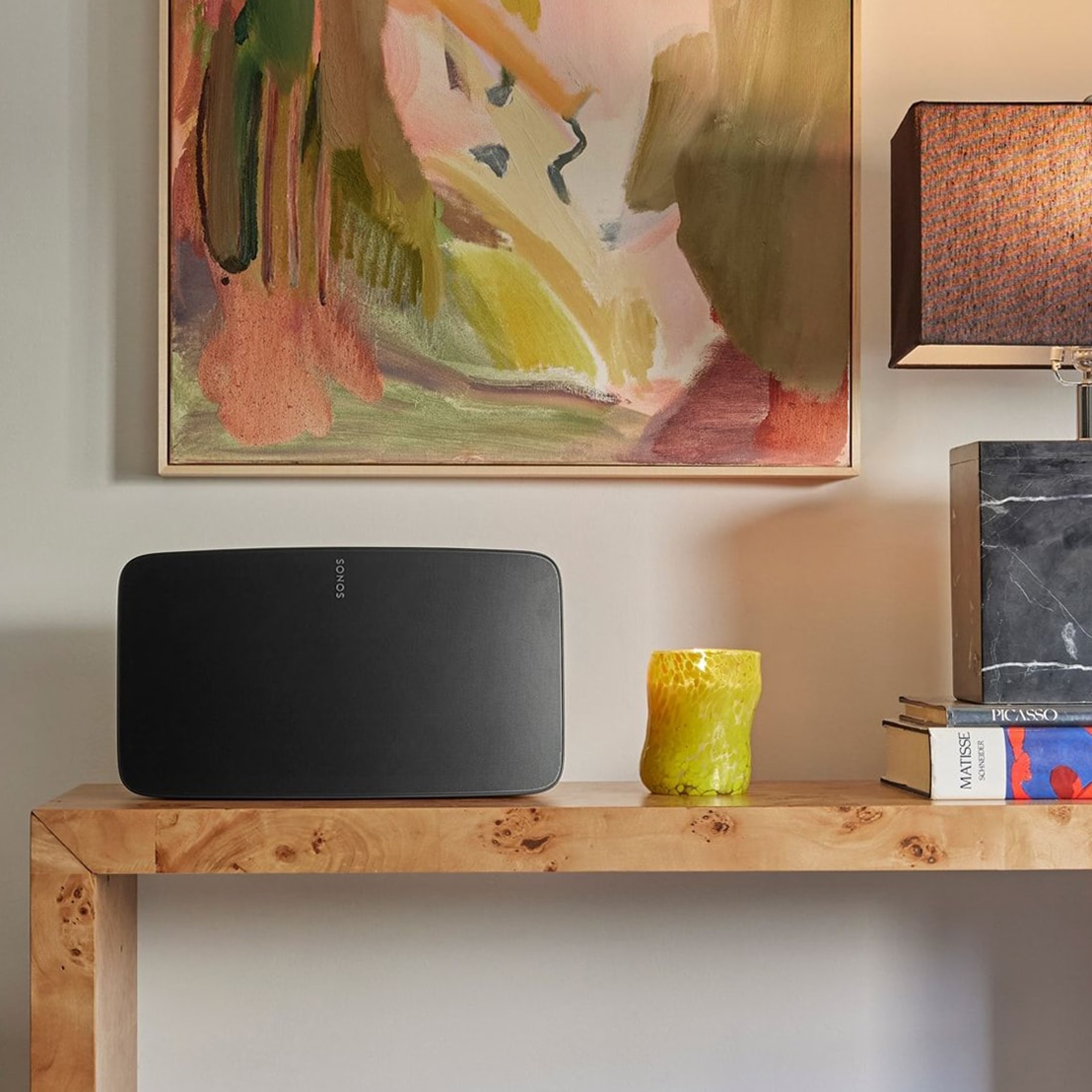 En svart Sonos Five prydligt placerad på en skänk bredvid en lampa