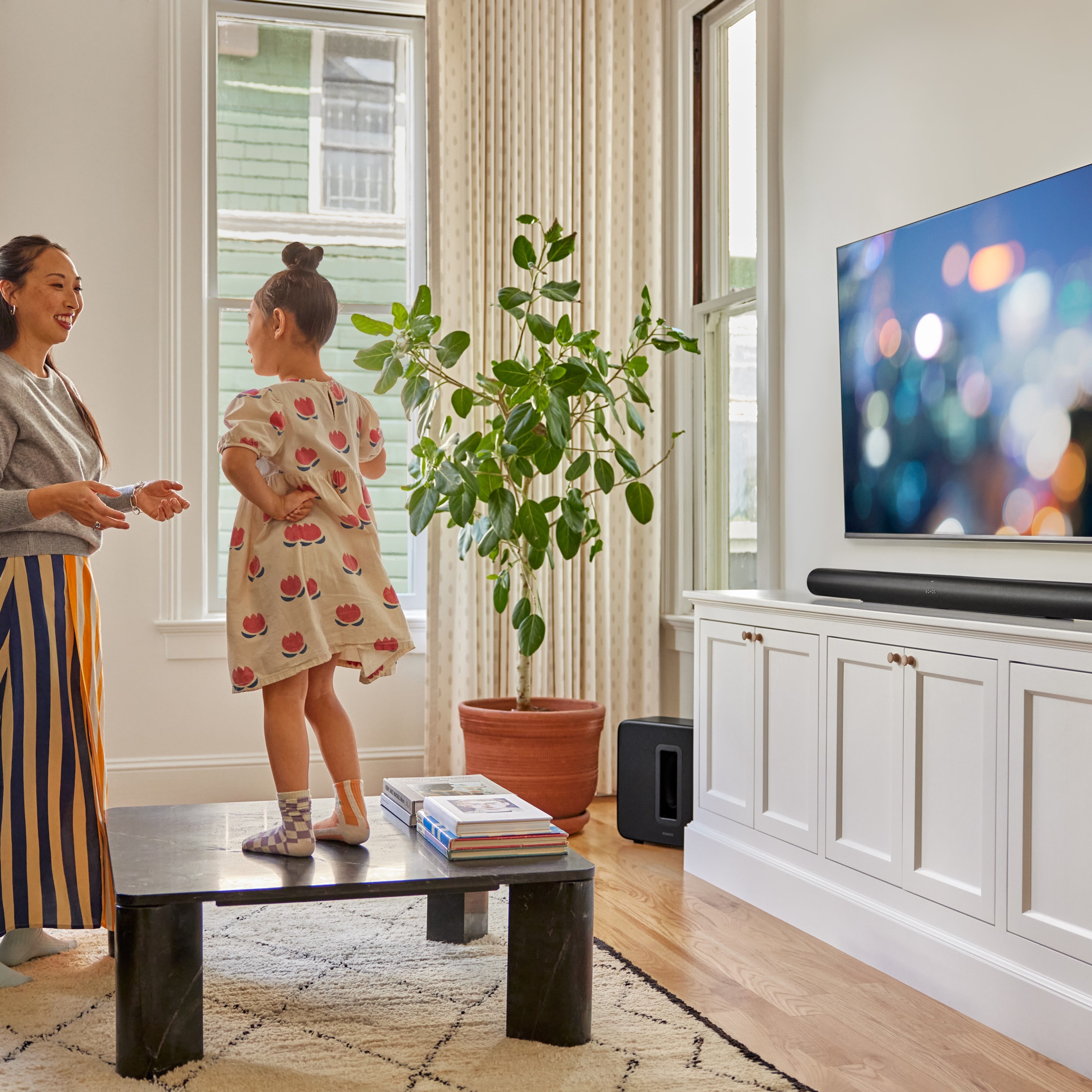 Mamma och dotter som leker framför en tv med en svart Arc Ultra