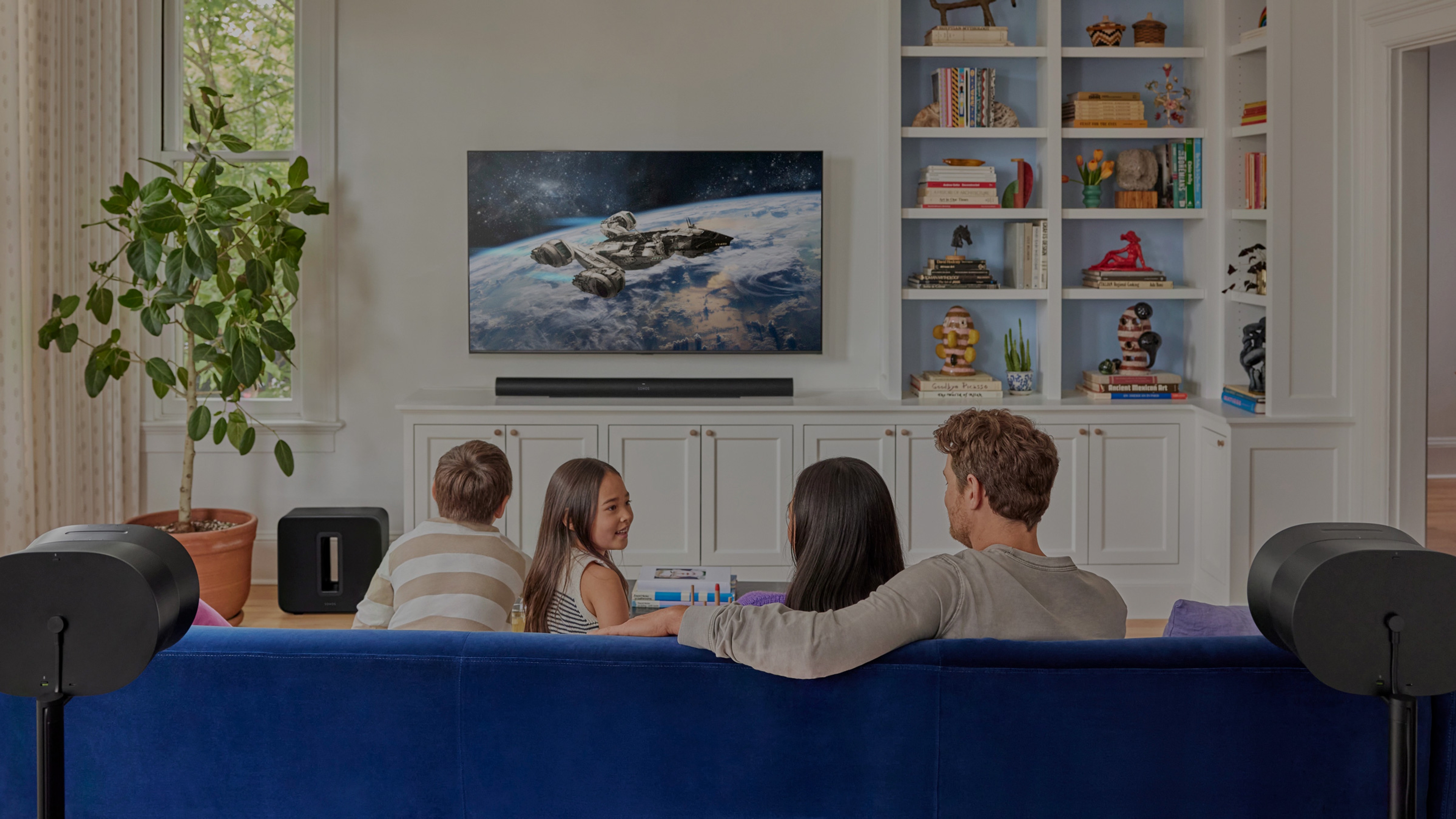 Una familia mira televisión en la sala con un set de teatro en casa con Sonos Arc Ultra, Sub 4 y Era 300