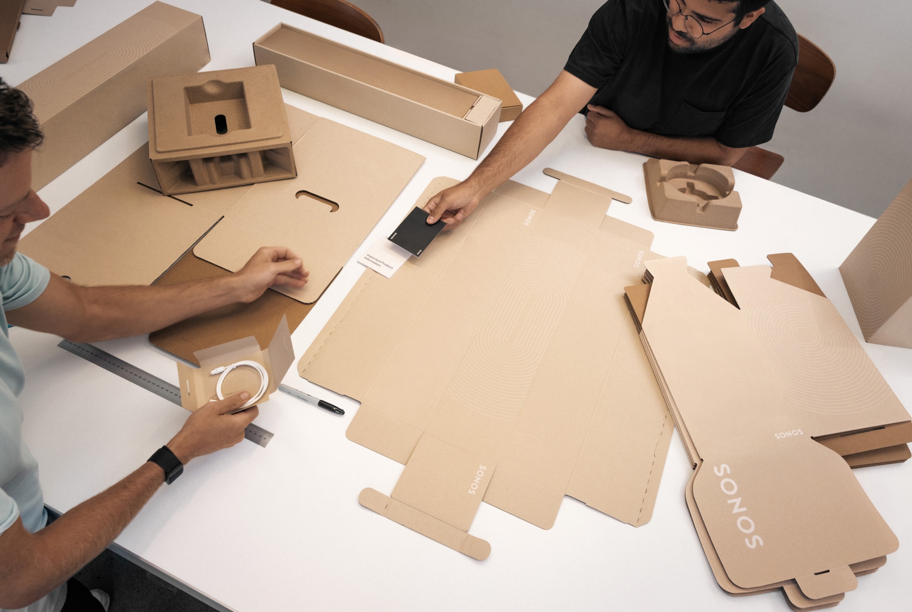 Deux employés de Sonos inspectant l'emballage recyclable d'un produit Sonos