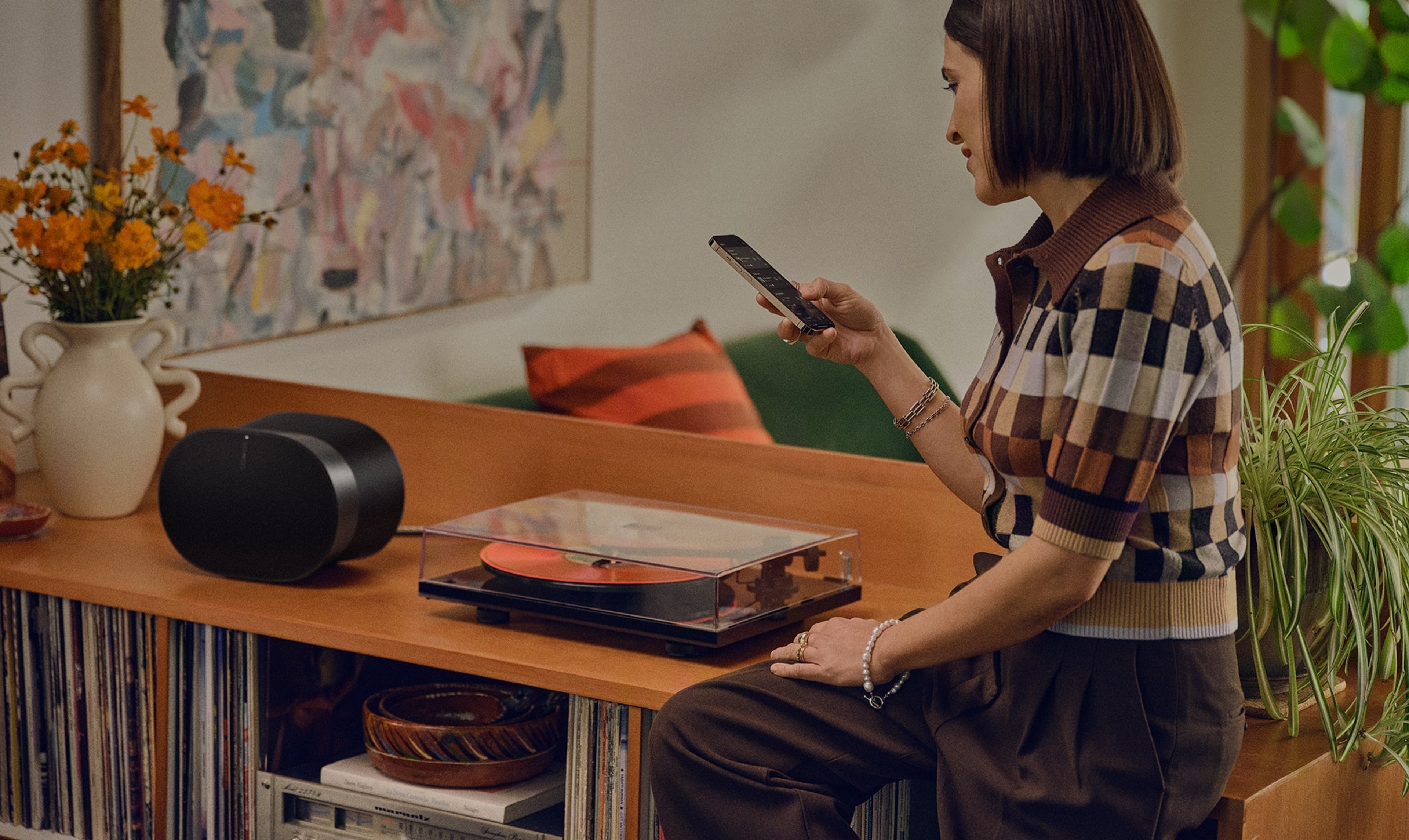 Une femme en train de contrôler son Sonos Era 300 noir depuis son smartphone