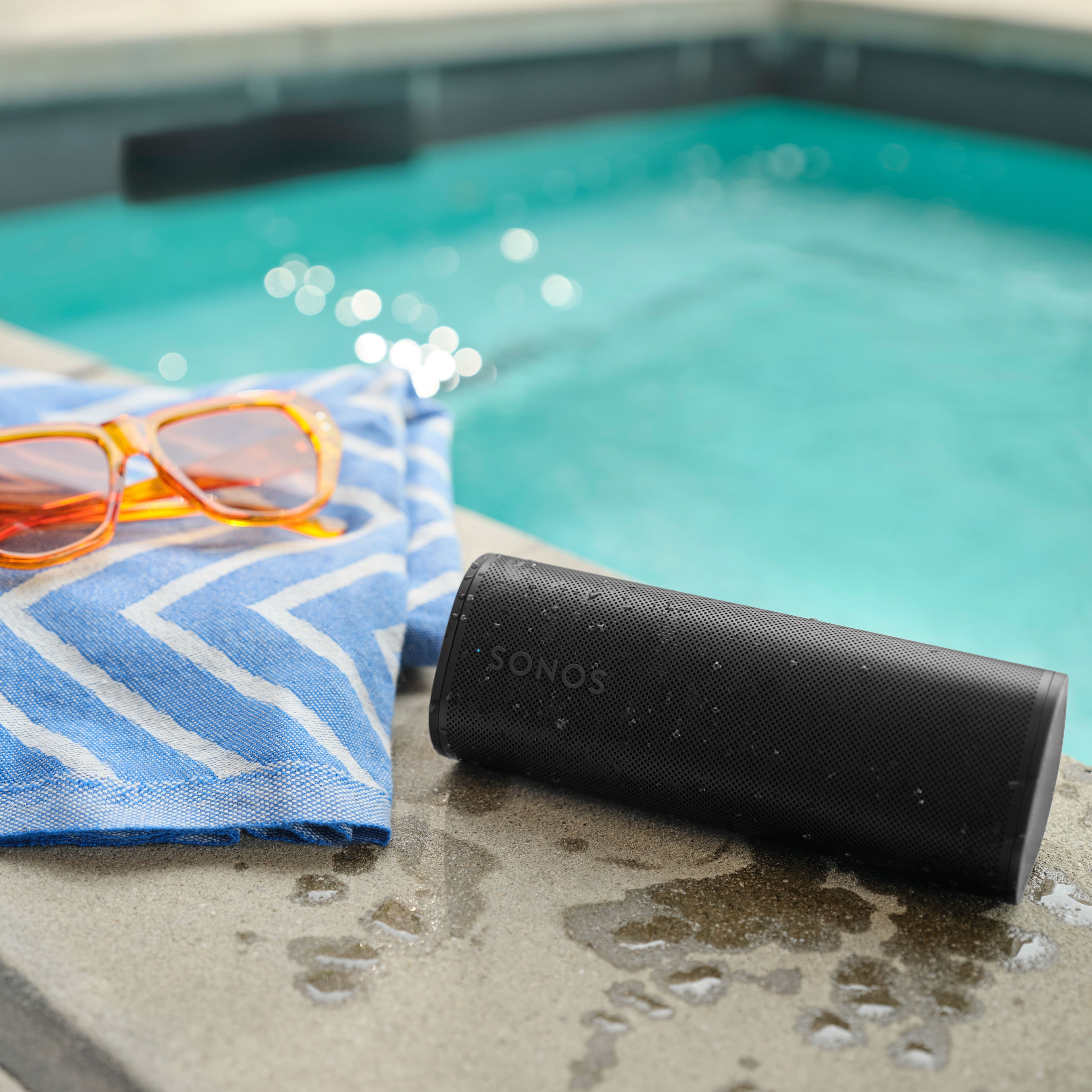Roam 2 in Schwarz an einem Pool mit einem Handtuch