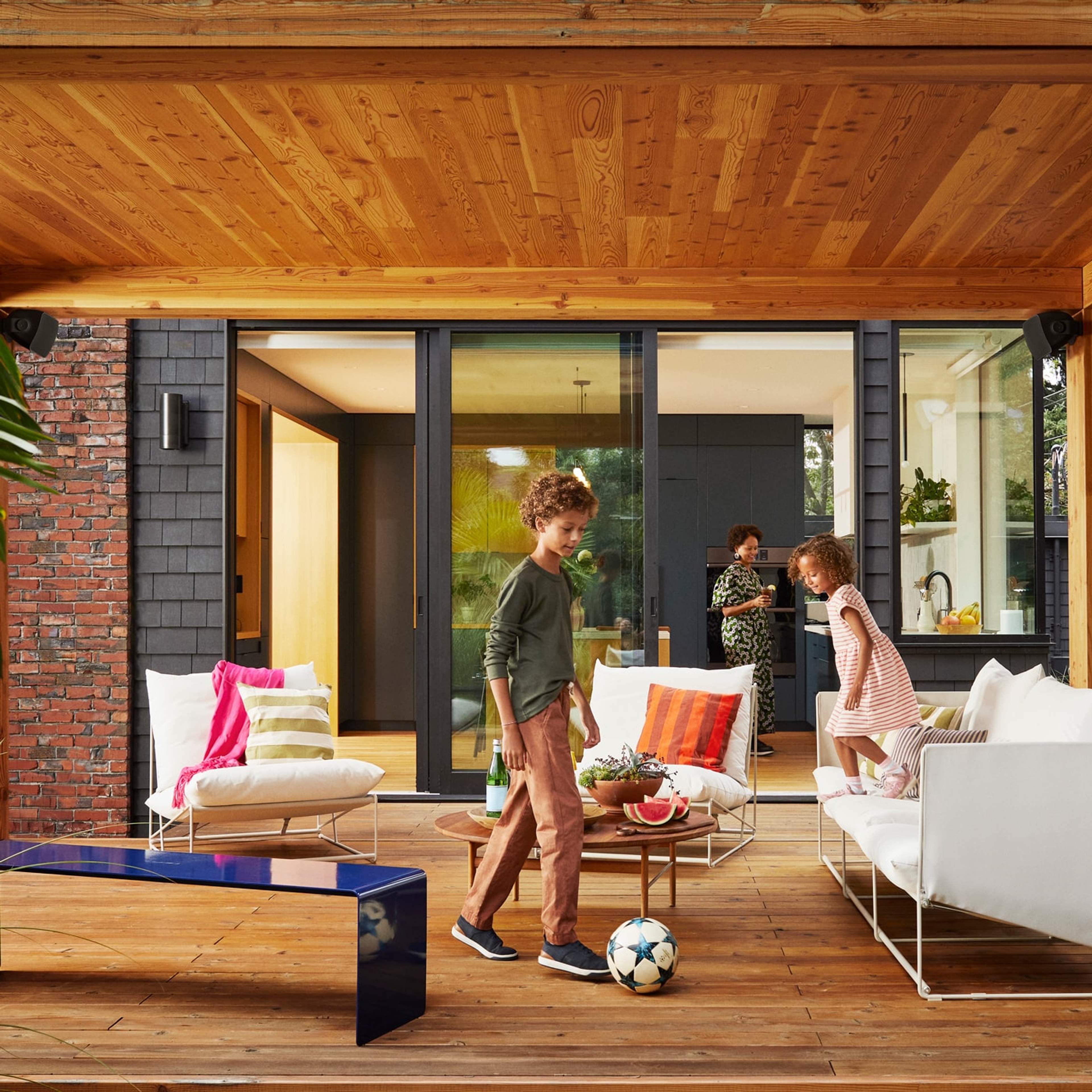 Kinder, die auf einer Terrasse Fußball spielen, und Outdoor Speaker von Sonos und Sonance