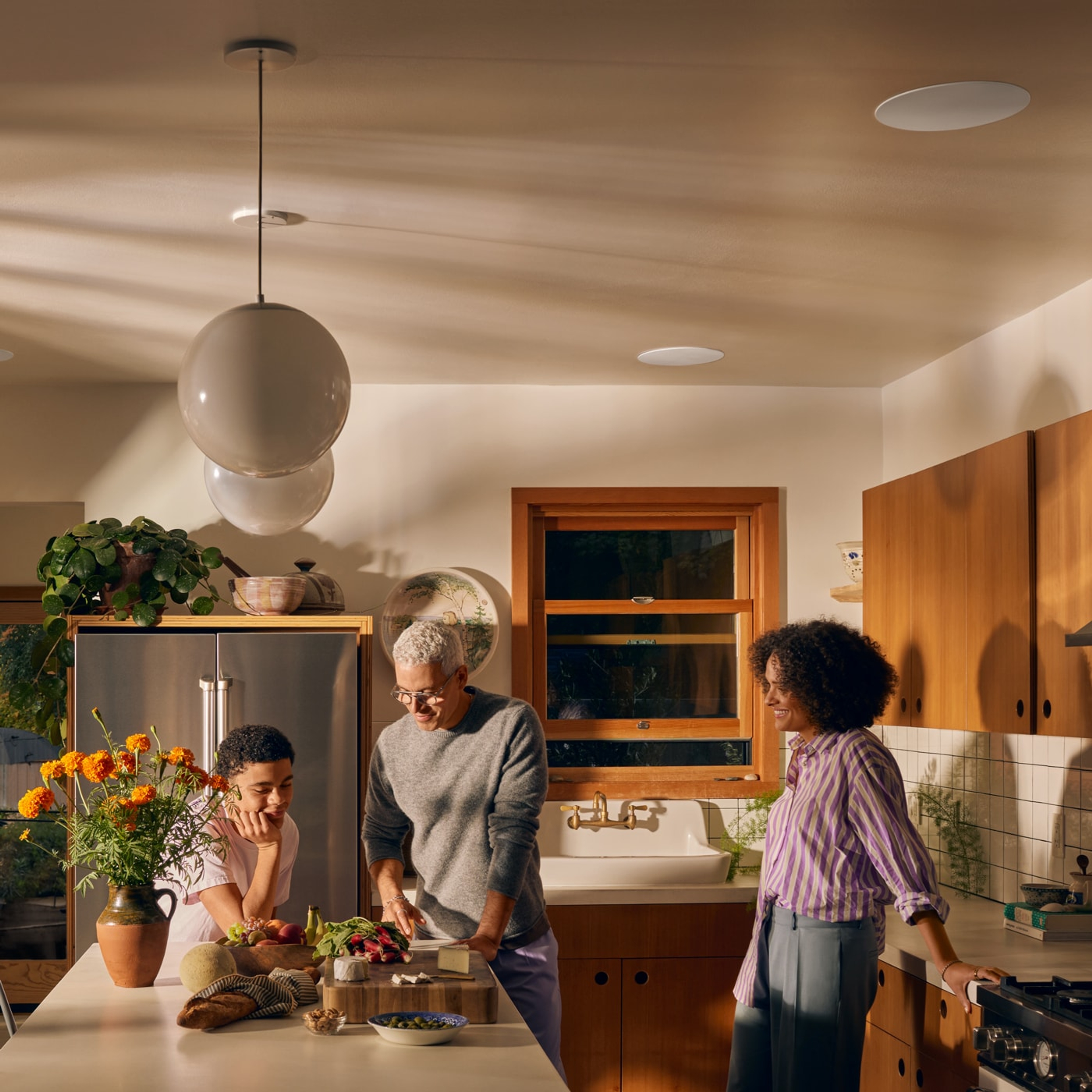Unos altavoces In-Ceiling instalados en la cocina con una familia cocinando