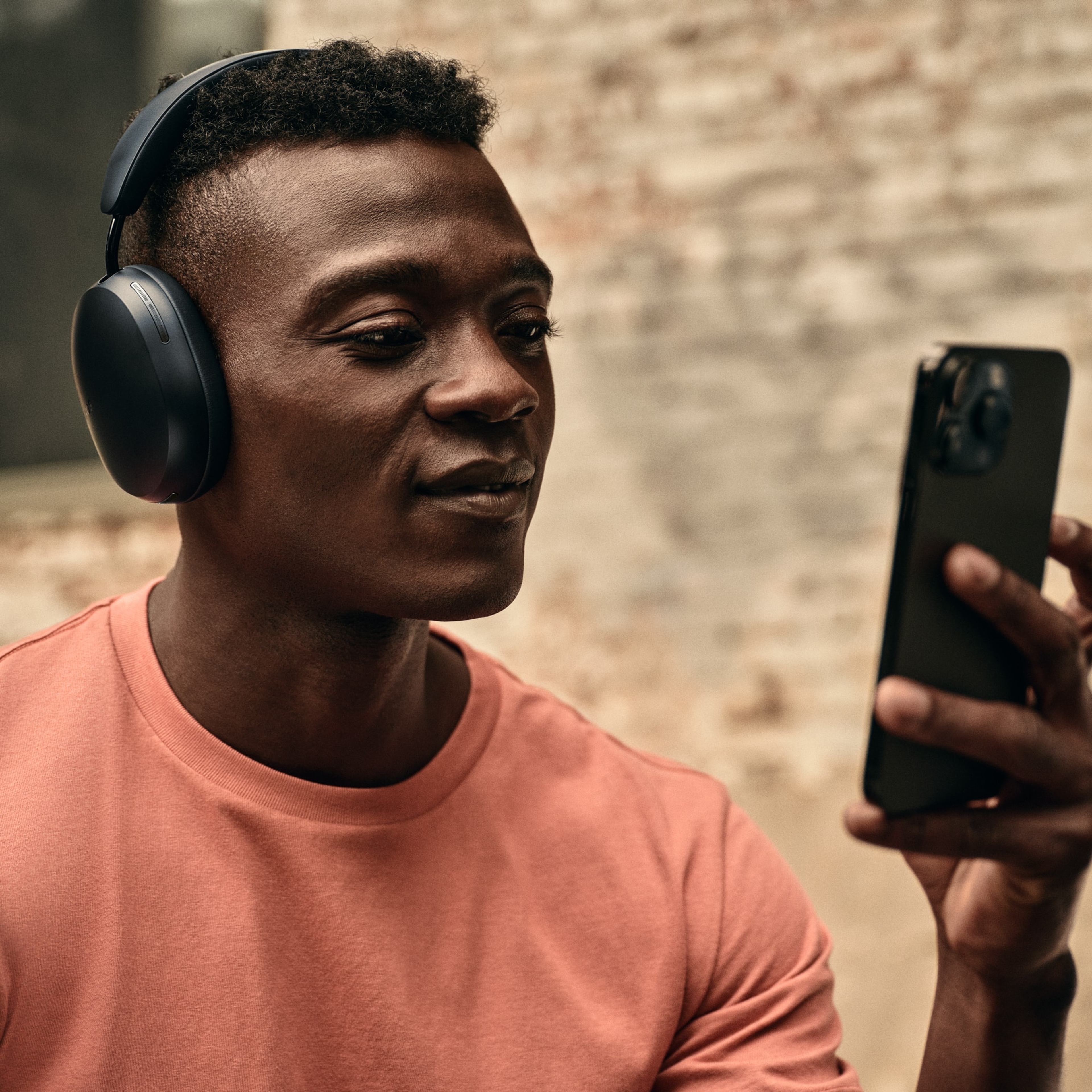 Osoba w czarnych słuchawkach Sonos Ace podczas korzystania z telefonu