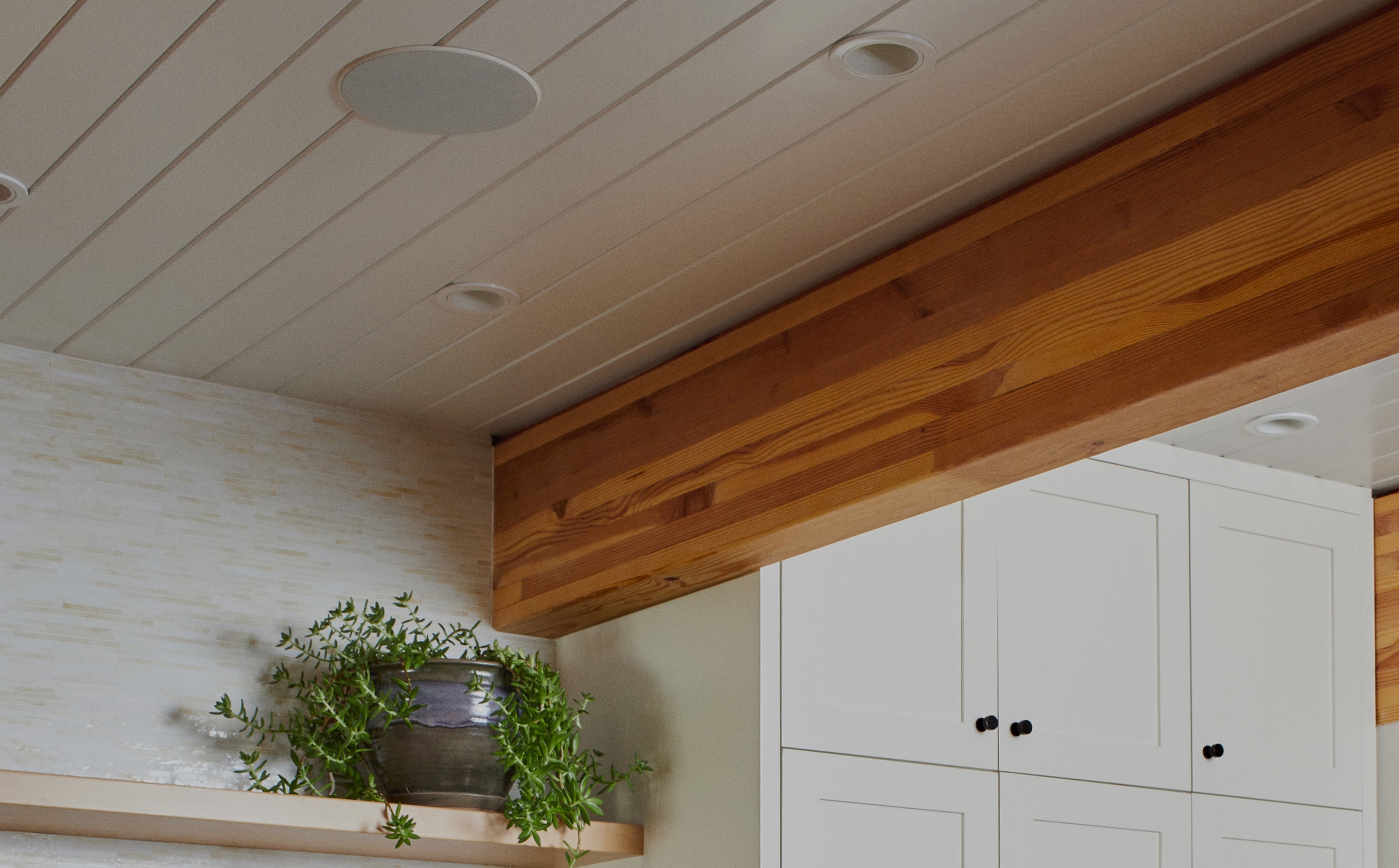 Primer plano de un altavoz In-Ceiling de Sonos y Sonance instalado en el techo, encima de una estantería