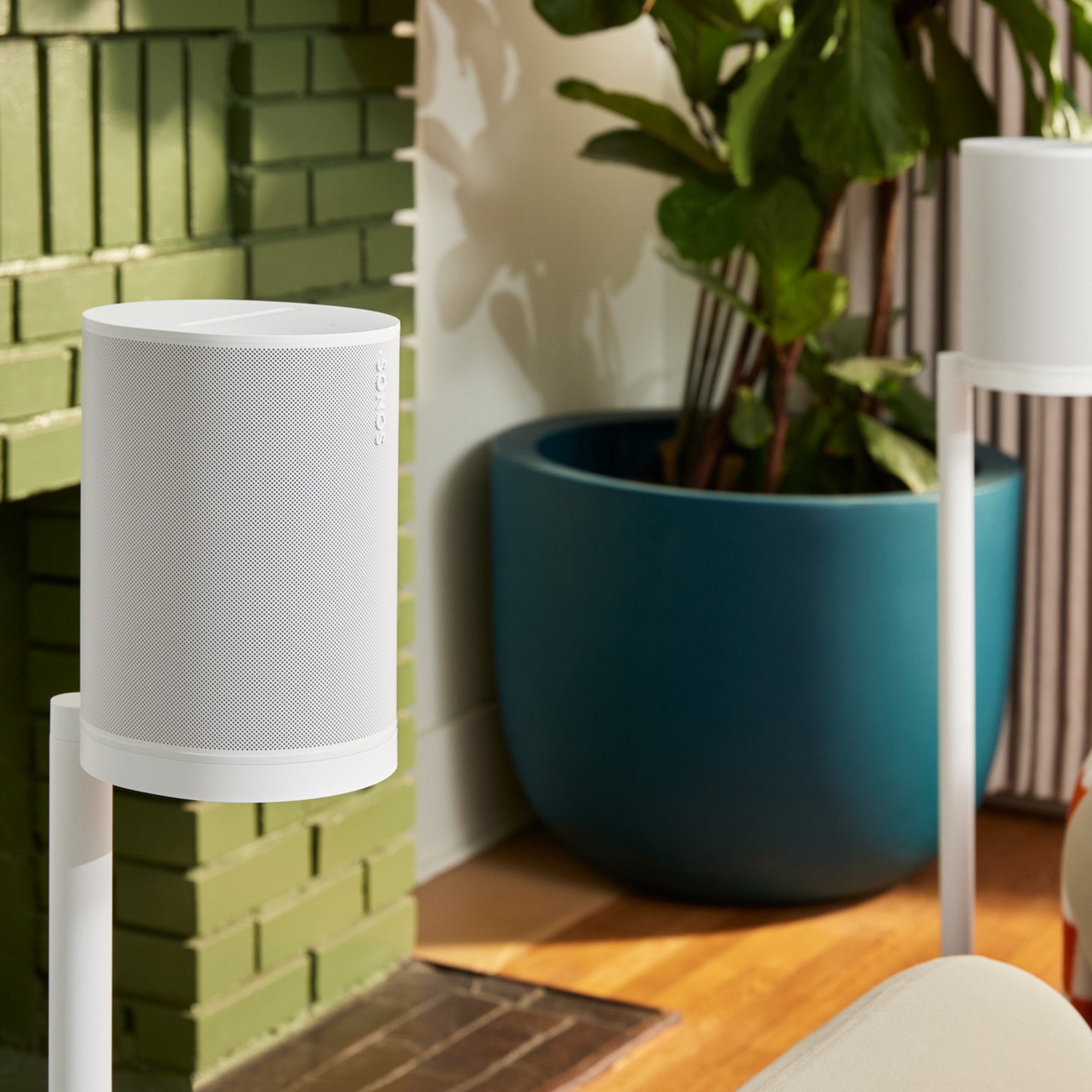 A pair of white Sonos Era 100 SL speakers on their corresponding stands being used for surround sound in a living room