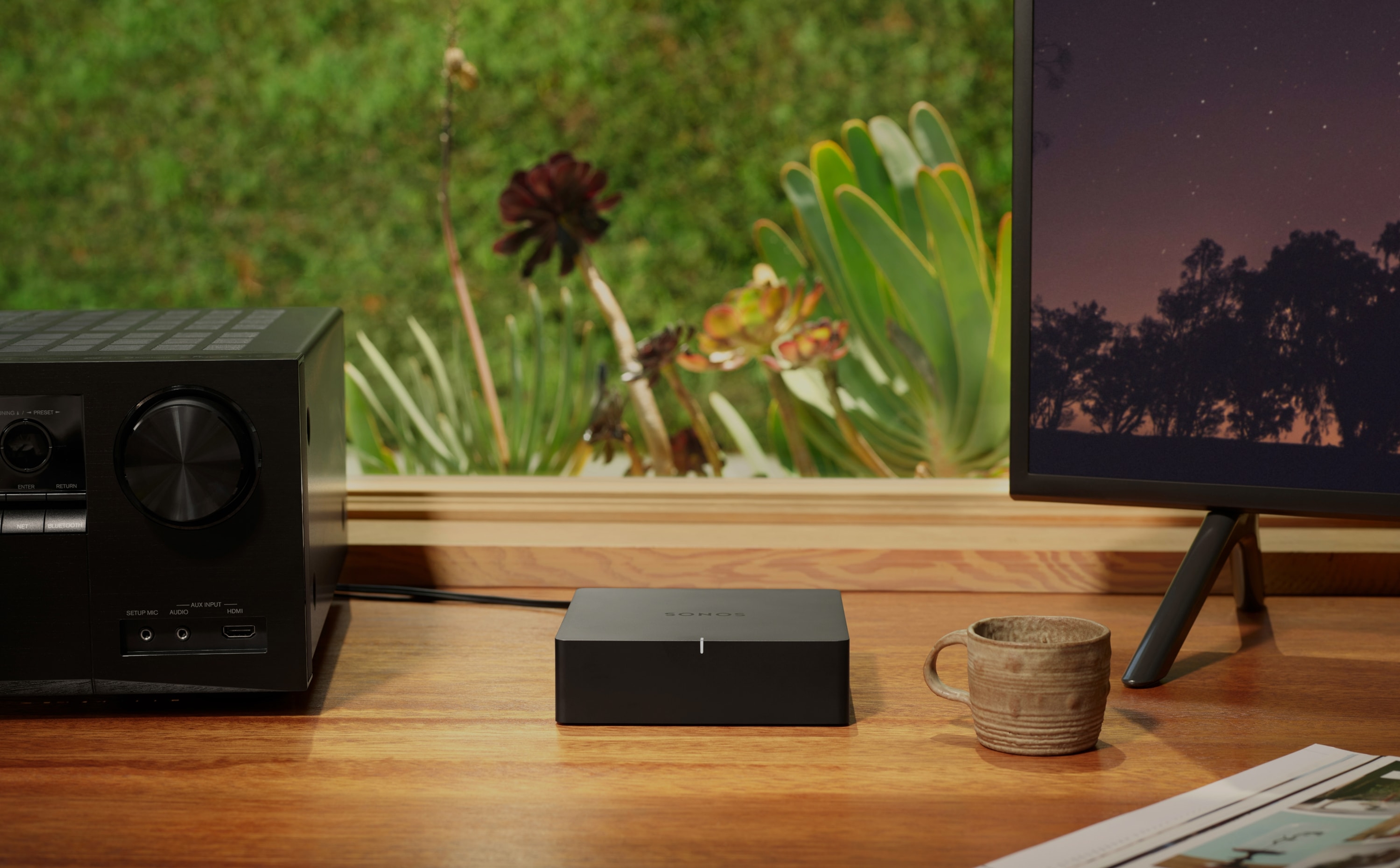 Sonos Port sobre un escritorio junto a un receptor estéreo