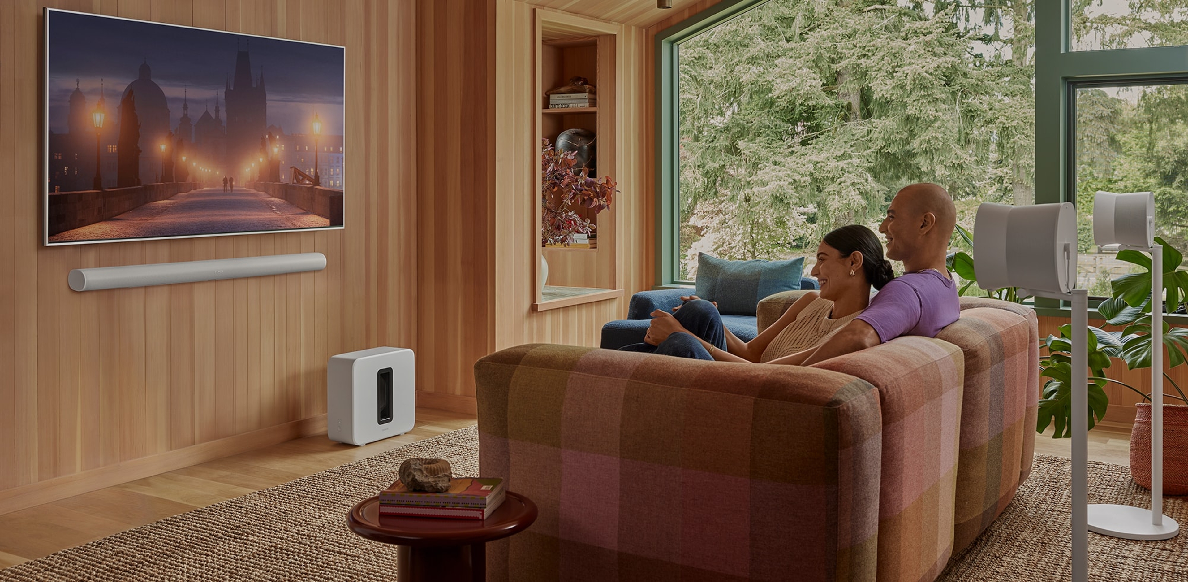 Pariskunta katsomassa televisiota käyttämällä seinään asennettua valkoista Arc Ultraa, Sub 4 -subwooferia ja Era 300 -surround-kaiutinparia