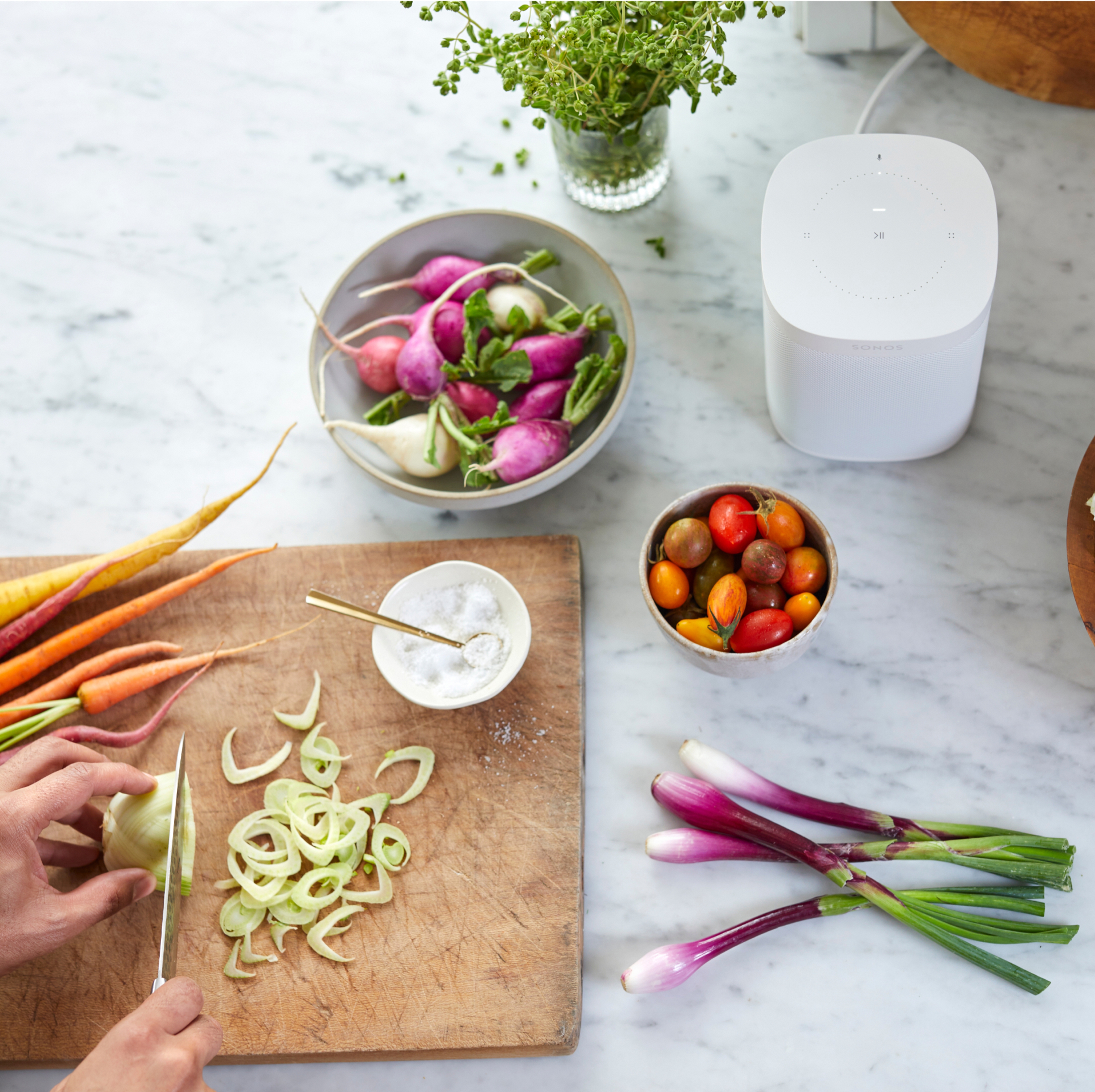 Sonos One blanc avec des légumes et une planche à découper