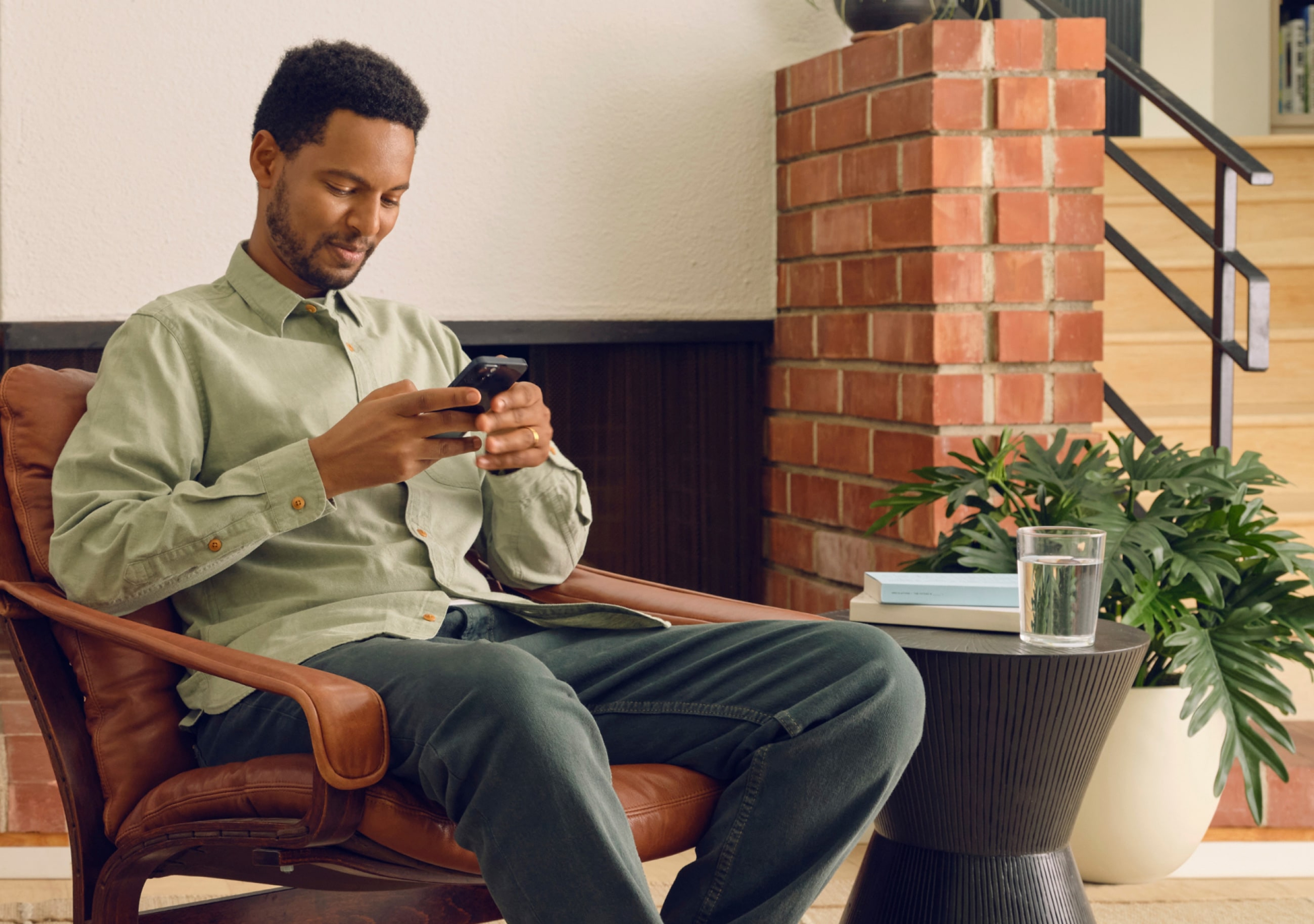 Ein in einem Wohnzimmer sitzender User mit der Sonos App auf dem Smartphone