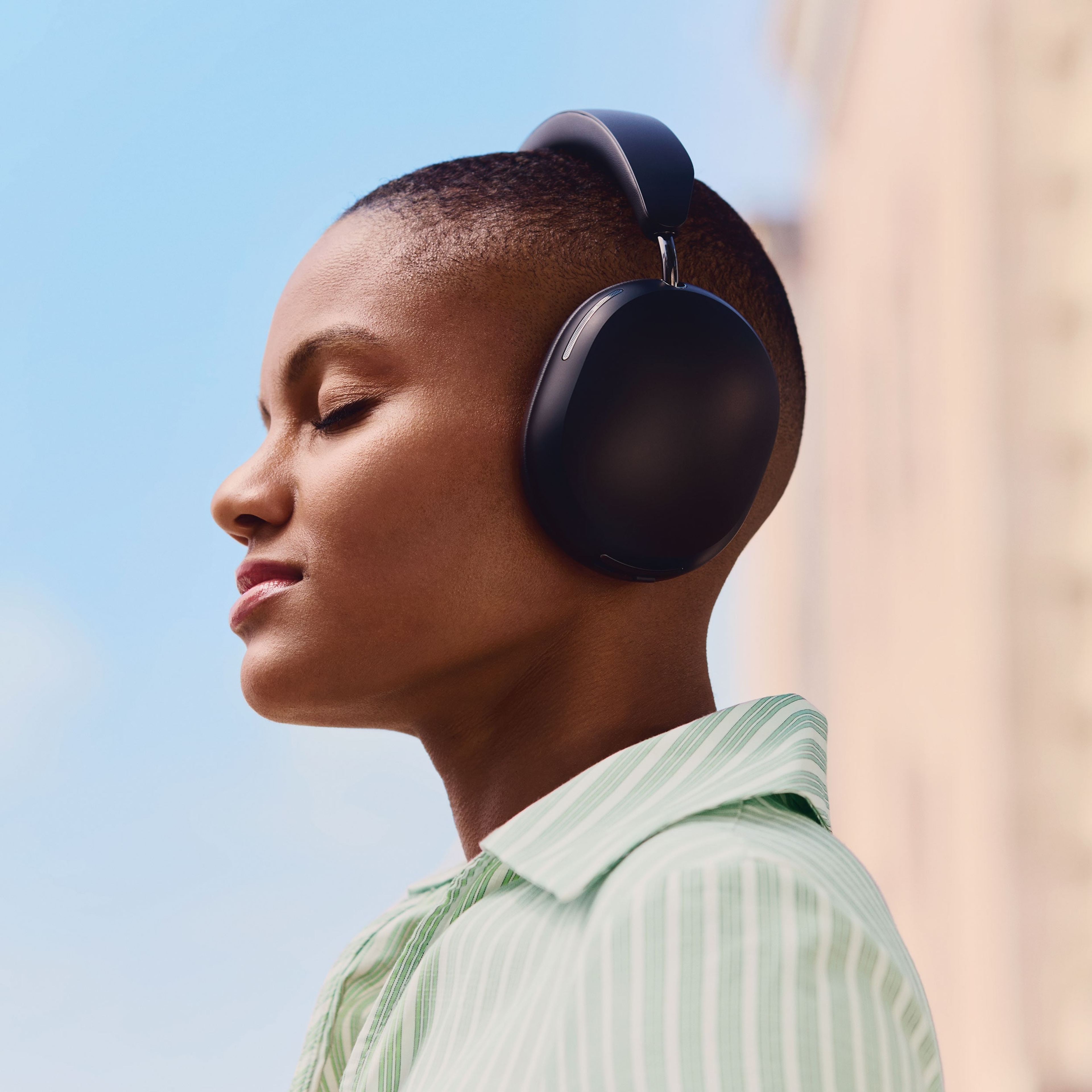Person som lyssnar på musik på svarta Sonos Ace-hörlurar under en stadspromenad