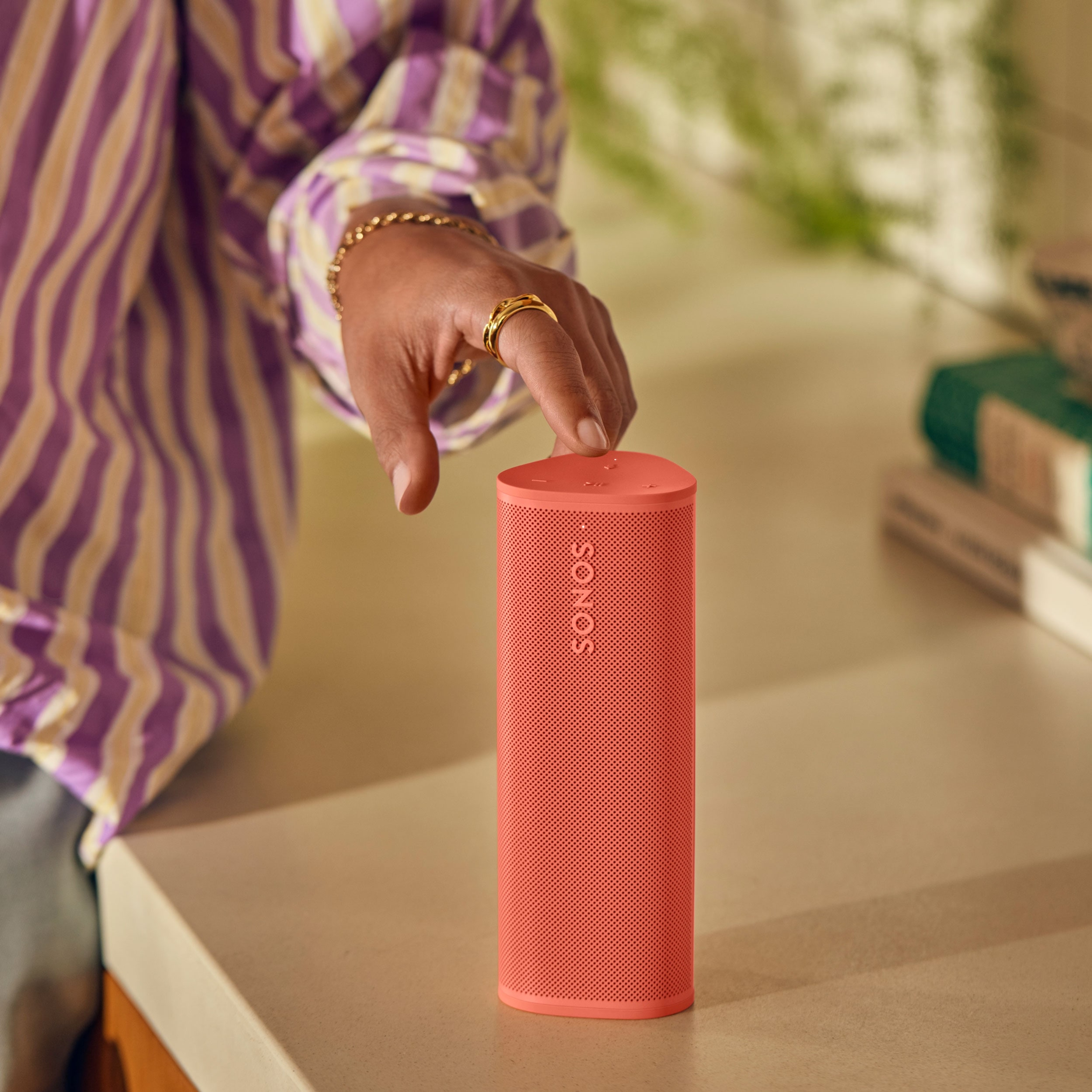 Closeup view of a hand tapping Sonos Roam 2 in Sunset